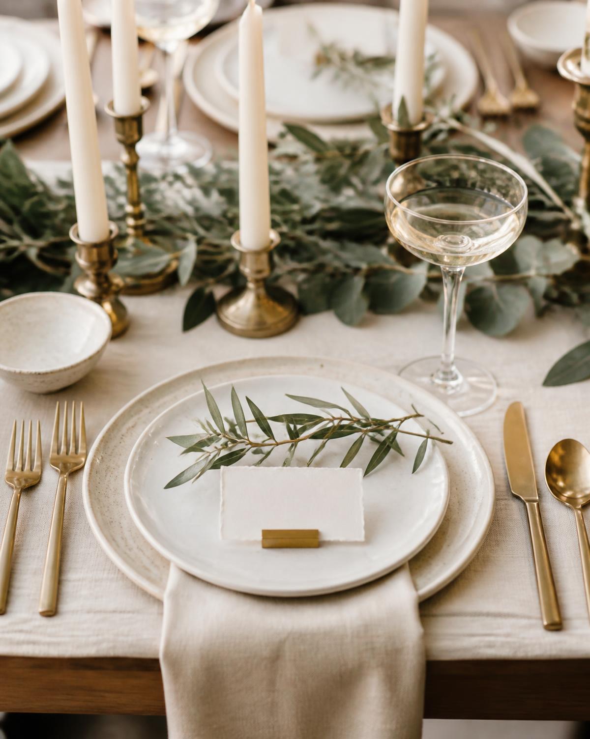 Styled tablescape place setting with linen, greenery and brass candlesticks